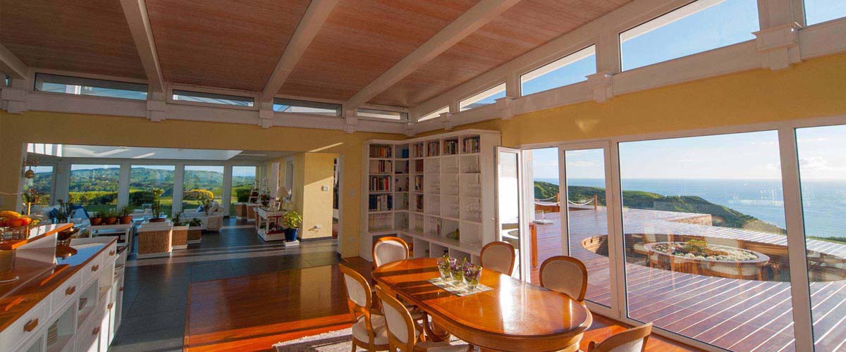 Oceanside stay, kitchen-dining area with cookbook library and view over the deck and the ocean. Atrium relaxing area with view over rolling hills into the valley